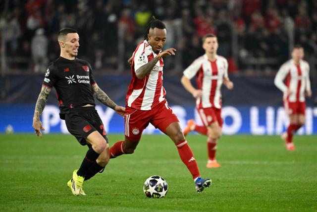 Bayer Leverkusen's Spanish defender #20 Alex Grimaldo (L) and Olympiakos' Portuguese forward #10 Gelson Martins (C) fight for the ball during the UEFA Champions League knockout round play-off first leg football match between Olympiacos FC (GRE) and Bayer Leverkusen (GER) at the Karaiskakis Stadium in Piraeus, near Athens, on February 18, 2026. (Photo by Aris MESSINIS / AFP)