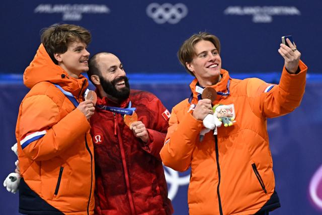 Silver medallist Netherlands' Melle van 't Wout, gold medallis sCanada's Steven Dubois and bronze medallis Netherlands' Jens van 't Wout pose for a selfie at the podium of the short track speed skating men's 500m final during the Milano Cortina 2026 Winter Olympic Games at Milano Ice Skating Arena in Milan on February 18, 2026. (Photo by Gabriel BOUYS / AFP)