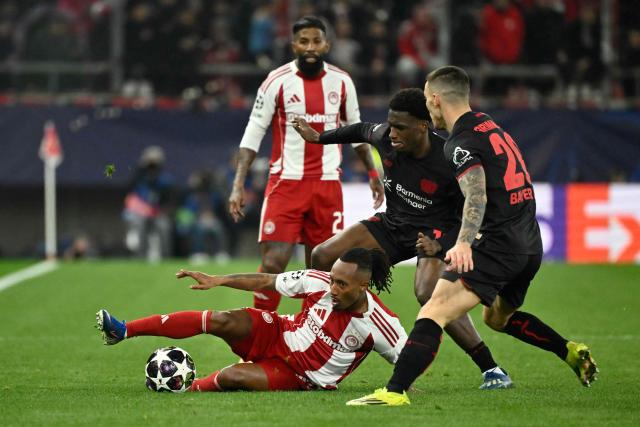 Olympiakos' Portuguese forward #10 Gelson Martins (CL) and Bayer Leverkusen's Dutch forward #19 Ernest Poku (CR) fight for the ball during the UEFA Champions League knockout round play-off first leg football match between Olympiacos FC (GRE) and Bayer Leverkusen (GER) at the Karaiskakis Stadium in Piraeus, near Athens, on February 18, 2026. (Photo by Aris MESSINIS / AFP)