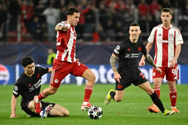 Olympiakos' Argentine midfielder #32 Santiago Hezze (CL) fights for the ball with Bayer Leverkusen's Algerian midfielder #30 Ibrahim Maza (L) and Bayer Leverkusen's Spanish defender #20 Alex Grimaldo (CR) during the UEFA Champions League knockout round play-off first leg football match between Olympiacos FC (GRE) and Bayer Leverkusen (GER) at the Karaiskakis Stadium in Piraeus, near Athens, on February 18, 2026. (Photo by Aris MESSINIS / AFP)