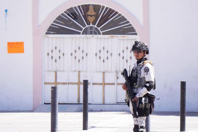 A Mexican National Guard soldier stands guard in front of a church a day after an armed attack on a playground in San Francisco del Rincon, Guanajuato state, Mexico on February 18, 2026. An armed attack in the state of Guanajuato, in central Mexico, left a 36-year-old man dead and at least eight youths injured on a playground on February 17, 2026, another violent episode in the region that provoked terror among local neighbors. (Photo by MARIO ARMAS / AFP)