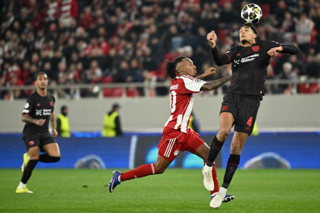 Olympiakos' Portuguese forward #10 Gelson Martins (C) and Bayer Leverkusen's English defender #04 Jarell Quansah (R) fight for the ball during the UEFA Champions League knockout round play-off first leg football match between Olympiacos FC (GRE) and Bayer Leverkusen (GER) at the Karaiskakis Stadium in Piraeus, near Athens, on February 18, 2026. (Photo by Aris MESSINIS / AFP)