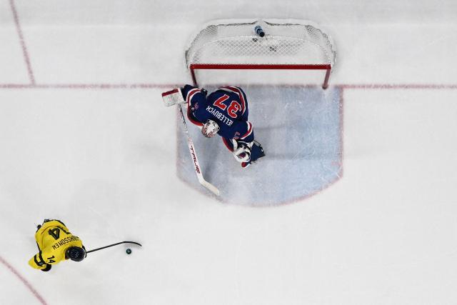 Sweden's #14 Joel Eriksson Ek (L) fights for the puck with USA's #37 Connor Hellebuyck during the men's play-off quarter-final ice hockey match between USA and Sweden at the Milano Santagiulia Ice Hockey Arena during the Milano Cortina 2026 Winter Olympic Games in Milan, on February 18, 2026. (Photo by Alexander NEMENOV / AFP)