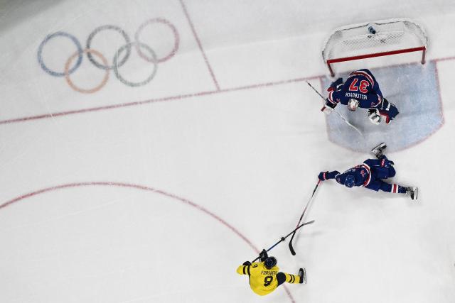 Sweden's #09 Filip Forsberg (L) fights for the puck with USA's #74 Jaccob Slavin in fornt of USA's #37 Connor Hellebuyck during the men's play-off quarter-final ice hockey match between USA and Sweden at the Milano Santagiulia Ice Hockey Arena during the Milano Cortina 2026 Winter Olympic Games in Milan, on February 18, 2026. (Photo by Alexander NEMENOV / AFP)