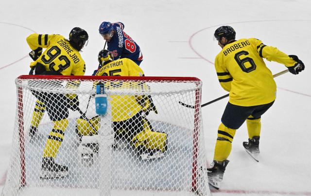 USA's #85 Jake Sanderson (C) controls the puck during the men's play-off quarter-final ice hockey match between USA and Sweden at the Milano Santagiulia Ice Hockey Arena during the Milano Cortina 2026 Winter Olympic Games in Milan, on February 18, 2026. (Photo by Alexander NEMENOV / POOL / AFP)