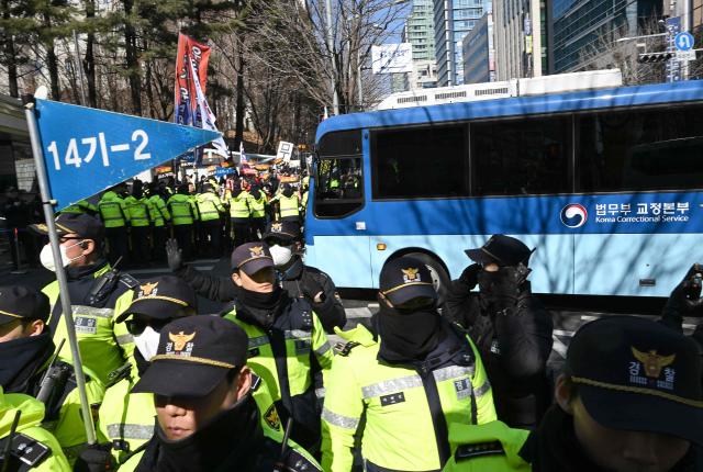 A blue bus believed to be transporting South Korea's impeached former president Yoon Suk Yeol arrives at the Seoul Central District Court in Seoul on February 19, 2026. A South Korean court will rule on February 19, on insurrection charges against ex-president Yoon Suk Yeol, weighing whether he should be sentenced to death for his failed bid to impose military rule. (Photo by Jung Yeon-je / AFP)