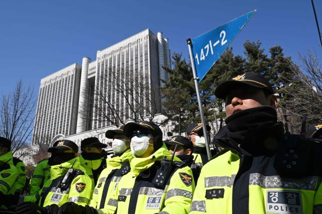Police officers stand guard at the entrance of the Seoul Central District Court in Seoul on February 19, 2026. A South Korean court will rule on February 19, on insurrection charges against ex-president Yoon Suk Yeol, weighing whether he should be sentenced to death for his failed bid to impose military rule. (Photo by Jung Yeon-je / AFP)
