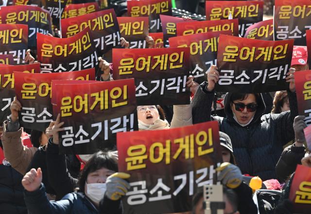 Supporters of South Korea's impeached former president Yoon Suk Yeol hold up placards reading "Yoon again!" in front of the Seoul Central District Court in Seoul on February 19, 2026. A South Korean court will rule on February 19, on insurrection charges against ex-president Yoon Suk Yeol, weighing whether he should be sentenced to death for his failed bid to impose military rule. (Photo by Jung Yeon-je / AFP)