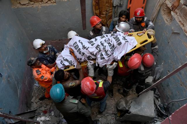 Rescue workers recover a victim’s body amid the debris of a collapsed building following an explosion, in Karachi on February 19, 2026. (Photo by Rizwan TABASSUM / AFP)
