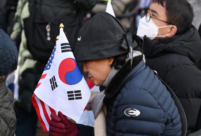 Supporters of South Korea's impeached former president Yoon Suk Yeol react as they watch a live stream of Yoon's trial on his insurrection charges near the Seoul Central District Court in Seoul on February 19, 2026. A South Korean court found ex-president Yoon Suk Yeol guilty of insurrection on February 19, and sentenced him to life in prison, saying his martial law declaration in December 2024 was a plot to "paralyse" the National Assembly. (Photo by Jung Yeon-je / AFP)