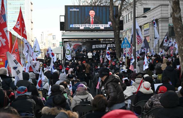 Supporters of South Korea's impeached former president Yoon Suk Yeol gather to watch a live stream of Yoon's trial on his insurrection charges near the Seoul Central District Court in Seoul on February 19, 2026. A South Korean court found ex-president Yoon Suk Yeol guilty of insurrection on February 19, and sentenced him to life in prison, saying his martial law declaration in December 2024 was a plot to "paralyse" the National Assembly. (Photo by Jung Yeon-je / AFP)