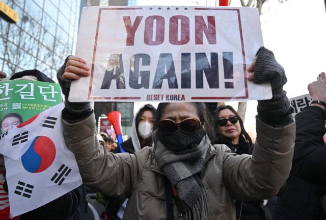 Supporters of South Korea's impeached former president Yoon Suk Yeol react as they watch a live stream of Yoon's trial on his insurrection charges near the Seoul Central District Court in Seoul on February 19, 2026. A South Korean court found ex-president Yoon Suk Yeol guilty of insurrection on February 19, and sentenced him to life in prison, saying his martial law declaration in December 2024 was a plot to "paralyse" the National Assembly. (Photo by Jung Yeon-je / AFP)