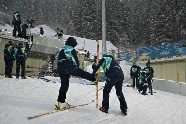 Staff mend the snow on the large hill jumping slope under a snowfall ahead of the ski jumping of the nordic combined team sprint large hill event at Predazzo Ski Jumping Stadium in Predazzo (Val di Fiemme) during the Milano Cortina 2026 Winter Olympic Games on February 19, 2026. (Photo by Javier SORIANO / AFP)