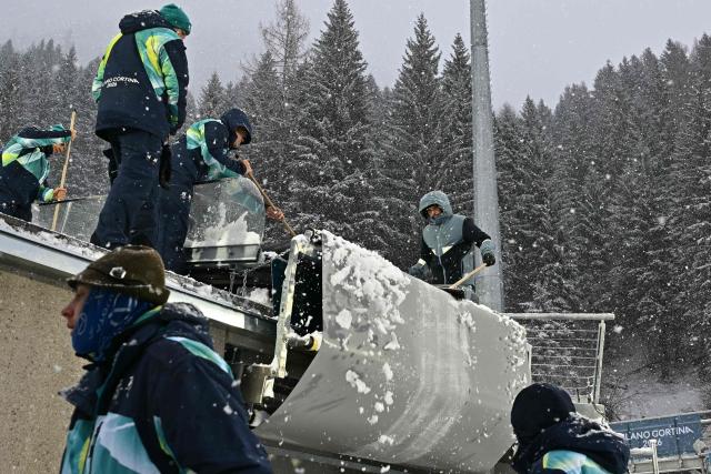 Staff clear the snow on the large hill jumping intrack under a snowfall ahead of the ski jumping of the nordic combined team sprint large hill event at Predazzo Ski Jumping Stadium in Predazzo (Val di Fiemme) during the Milano Cortina 2026 Winter Olympic Games on February 19, 2026. (Photo by Javier SORIANO / AFP)