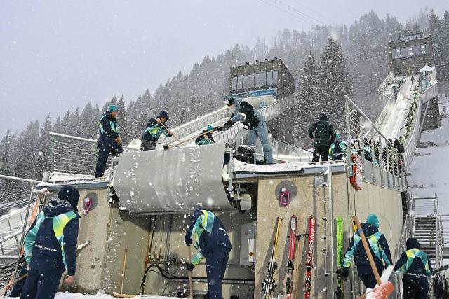 Staff mend the snow on the large hill jumping intrack under a snowfall ahead of the ski jumping of the nordic combined team sprint large hill event at Predazzo Ski Jumping Stadium in Predazzo (Val di Fiemme) during the Milano Cortina 2026 Winter Olympic Games on February 19, 2026. (Photo by Javier SORIANO / AFP)