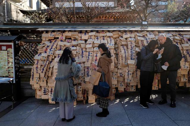 Visitors are seen beside wooden votive tablets placed by students and parents containing messages for academic success at Yushima Tenmangu Shrine in Tokyo on February 19, 2026, amid the annual entrance exam season. (Photo by Kazuhiro NOGI / AFP)