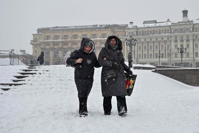 Women walk in central Moscow during heavy snowfall on February 19, 2026. (Photo by HECTOR RETAMAL / AFP)