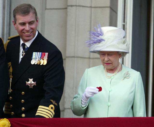 (FILES) Queen Elizath II hold a poppy dropped from a Lancaster bombe as she stands next to Prince Andrew on the balcony of Buckingham Palace during the celebrations marking the end of World War II in London on July 10, 2005. UK police said on February 19, 2026 officers were searching two addresses, one in eastern England and one west of London, following the arrest of ex-Prince Andrew on suspicion of misconduct in a public office. New revelations last week appeared to show Andrew sent convicted sex offender Jeffrey Epstein potentially confidential documents during his time as a UK trade envoy. (Photo by JAMES VELLACOTT / POOL / AFP)