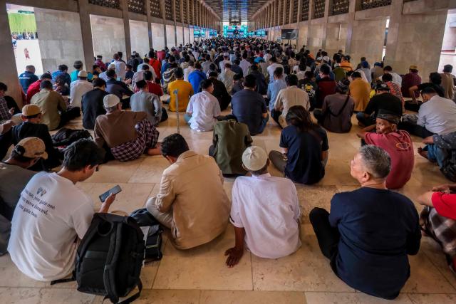 Muslim devotees gather to listen to a religious lecture while waiting to break their fast at Istiqlal Mosque in Jakarta on February 19, 2026, during the holy month of Ramadan, when Muslims worldwide abstain from food, drink and sexual relations from dawn to dusk. (Photo by BAY ISMOYO / AFP)