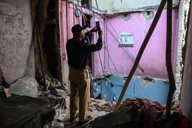 A policeman takes photographs at the site of a collapsed building following an explosion in Karachi on February 19, 2026. A building collapse caused by an explosion in Pakistan's southern megacity of Karachi killed at least 16 people on February 19, including children, officials said. (Photo by Rizwan TABASSUM / AFP)