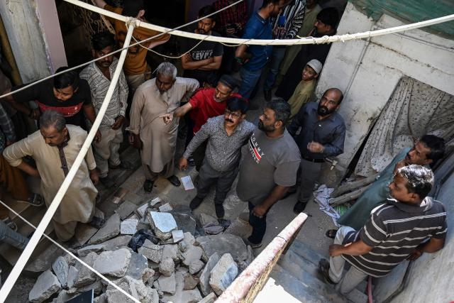 Residents gather at the site of a collapsed building following an explosion in Karachi on February 19, 2026. A building collapse caused by an explosion in Pakistan's southern megacity of Karachi killed at least 16 people on February 19, including children, officials said. (Photo by Rizwan TABASSUM / AFP)