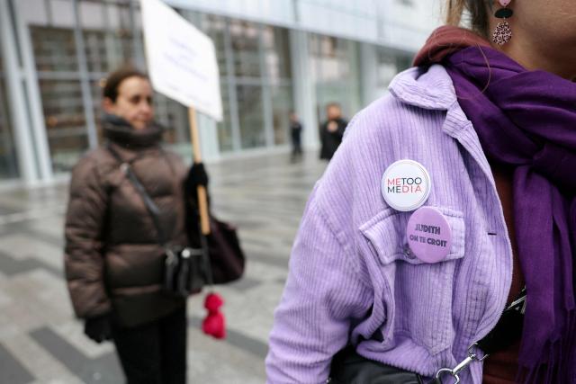 A woman bears a pin which reads as "Judith, we believe you" as Women gather outside the Paris courthouse in support of French actress Judith Godreche in Paris on February 19, 2026. Judith Godrèche, a leading figure of #MeToo in France, has been summoned on February 19 for a procedural hearing before the Paris court, following a defamation complaint by filmmaker Jacques Doillon, whom she accuses of raping her when she was 15. (Photo by Thomas SAMSON / AFP)