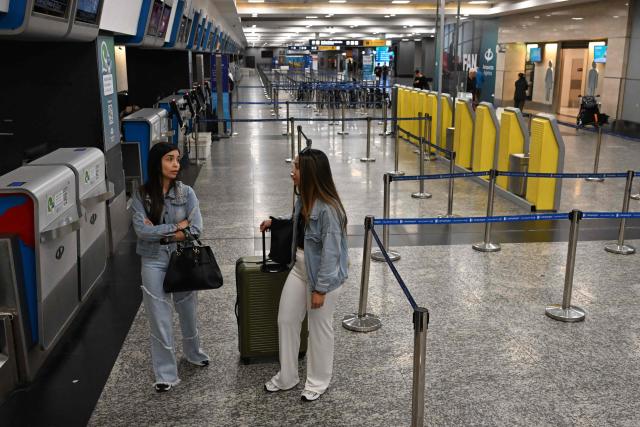 Passengers stand at an empty check-in counter at Jorge Newbery airport as flights are cancelled during a 24-hour general strike called by workers unions against President Javier Milei’s labor reform in Buenos Aires on February 19, 2026. The Argentine government faces on February 19 the fourth general strike of its administration, on the same day the Chamber of Deputies will debate a controversial labor reform pushed by ultraliberal President Javier Milei, which was already approved by the Senate last week. (Photo by Luis ROBAYO / AFP)