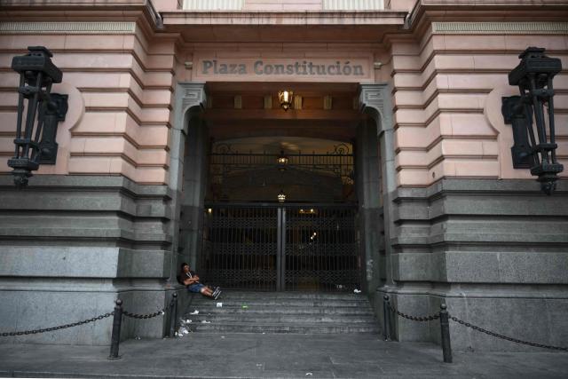 A man sleeps at the entrance of Constitucion train station, closed during a 24-hour general strike called by workers unions against President Javier Milei’s labor reform in Buenos Aires on February 19, 2026. The Argentine government faces on February 19 the fourth general strike of its administration, on the same day the Chamber of Deputies will debate a controversial labor reform pushed by ultraliberal President Javier Milei, which was already approved by the Senate last week. (Photo by Luis ROBAYO / AFP)