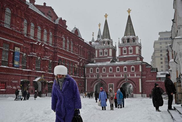 People walk near the State Historical Museum during heavy snowfall in central Moscow on February 19, 2026. (Photo by HECTOR RETAMAL / AFP)