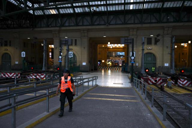 A police officer walks inside Constitucion train station, closed during a 24-hour general strike called by workers unions against President Javier Milei’s labor reform in Buenos Aires on February 19, 2026. The Argentine government faces on February 19 the fourth general strike of its administration, on the same day the Chamber of Deputies will debate a controversial labor reform pushed by ultraliberal President Javier Milei, which was already approved by the Senate last week. (Photo by Luis ROBAYO / AFP)