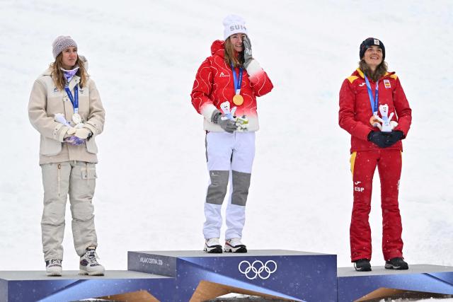 (From L) Silver medallist France's Emily Harrop, gold medallist Switzerland's Marianne Fatton and bronze medallist Spain's Ana Alonso Rodriguez celebrate on the podium after competing in the women's sprint ski mountaineering event during the Milano Cortina 2026 Winter Olympic Games at the Stelvio Ski Centre in Bormio (Valtellina) on February 19, 2026. (Photo by Fabrice COFFRINI / AFP)