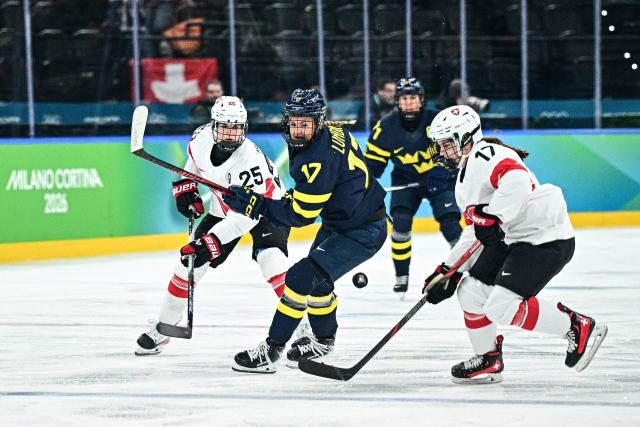 Sweden's #17 Sofie Lundin (C) fights for the puck with Switzerland's #17 Lara Christen (R)  during the women's bronze medal ice hockey match between Switzerland and Sweden at the Milano Santagiulia Ice Hockey Arena during the Milano Cortina 2026 Winter Olympic Games in Milan, on February 19, 2026. (Photo by JULIEN DE ROSA / AFP)