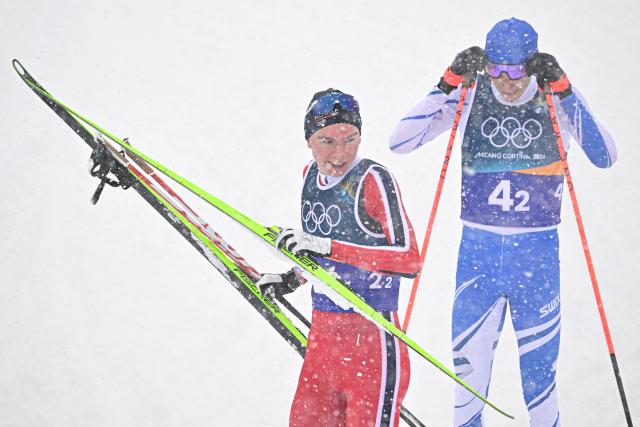 Norway's Jens Luraas Oftebro (L) celebrates crossing the finish line next to Finland's Eero Hirvonen during the cross-country of the nordic combined team sprint large hill event at Tesero Cross Country Stadium at Lago di Tesero (Val di Fiemme) during the Milano Cortina 2026 Winter Olympic Games on February 19, 2026. (Photo by Tobias SCHWARZ / AFP)