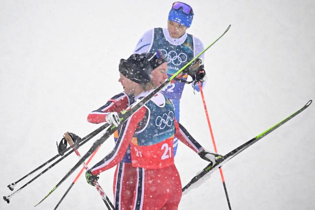 Gold medallists Norway's Jens Luraas Oftebro (C) and Norway's Andreas Skoglund celebrate next to Finland's Eero Hirvonen (top) at the end of the cross-country of the nordic combined team sprint large hill event at Tesero Cross Country Stadium at Lago di Tesero (Val di Fiemme) during the Milano Cortina 2026 Winter Olympic Games on February 19, 2026. (Photo by Tobias SCHWARZ / AFP)