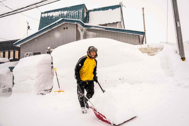 A man shovels snow in front of his house in Niseko, Hokkaido prefecture on February 19, 2026. (Photo by Yuichi YAMAZAKI / AFP)