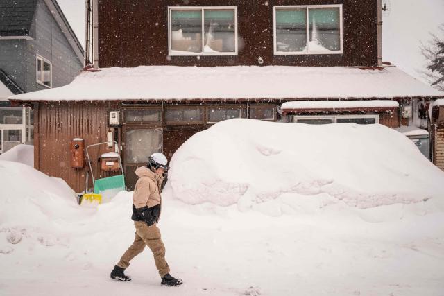 A man walks in a street during a snowfall in Niseko, Hokkaido prefecture on February 19, 2026. (Photo by Yuichi YAMAZAKI / AFP)