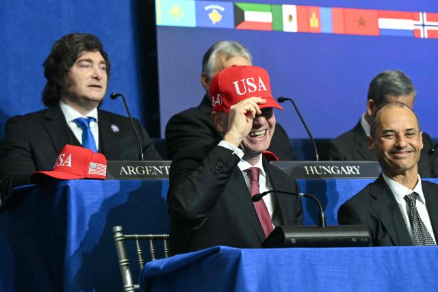 FIFA President Gianni Infantino puts on a "USA" hat as he attends the inaugural meeting of the "Board of Peace" hosted by US President Donald Trump at the US Institute of Peace in Washington, DC, on February 19, 2026. President Trump on Thursday gathers allies to inaugurate the "Board of Peace," his new institution focused on progress on Gaza but whose ambitions reach much further. Around two dozen world leaders or other senior officials have come to Washington for the meeting -- including several of Trump's authoritarian-leaning friends and virtually none of the European democrats that traditionally sign on to US initiatives. (Photo by SAUL LOEB / AFP)
