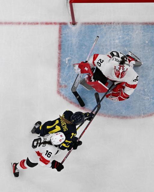 Sweden's #11 Josefin Bouveng (C) vies for the puck with Switzerland's #20 Andrea Braendli (top) and Switzerland's #16 Nicole Vallario during the women's bronze medal ice hockey match between Switzerland and Sweden at the Milano Santagiulia Ice Hockey Arena during the Milano Cortina 2026 Winter Olympic Games in Milan, on February 19, 2026. (Photo by Alexander NEMENOV / AFP)