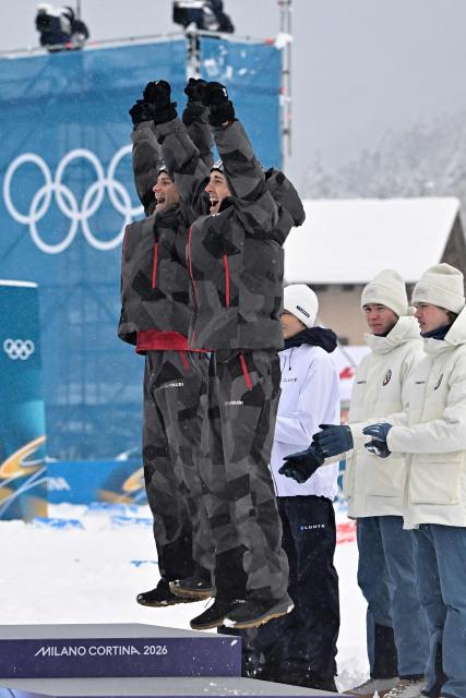 Bronze medallists Austria's Johannes Lamparter (L) and Stefan Rettenegger celebrate on the podium following the nordic combined team sprint large hill event at Tesero Cross Country Stadium at Lago di Tesero (Val di Fiemme) during the Milano Cortina 2026 Winter Olympic Games on February 19, 2026.  (Photo by Tobias SCHWARZ / AFP)