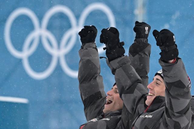 Bronze medallists Austria's Johannes Lamparter (L) and Stefan Rettenegger celebrate on the podium following the nordic combined team sprint large hill event at Tesero Cross Country Stadium at Lago di Tesero (Val di Fiemme) during the Milano Cortina 2026 Winter Olympic Games on February 19, 2026.  (Photo by Tobias SCHWARZ / AFP)