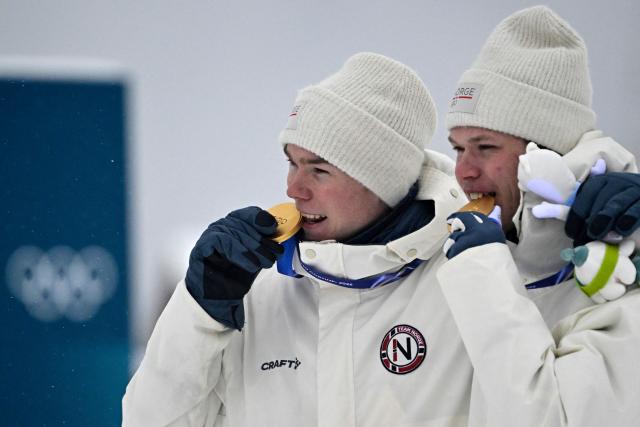 (From L) Gold medallist Norway's Jens Luraas Oftebro and Norway's Andreas Skoglund celebrate on the podium following the nordic combined team sprint large hill event at Tesero Cross Country Stadium at Lago di Tesero (Val di Fiemme) during the Milano Cortina 2026 Winter Olympic Games on February 19, 2026.  (Photo by Tobias SCHWARZ / AFP)