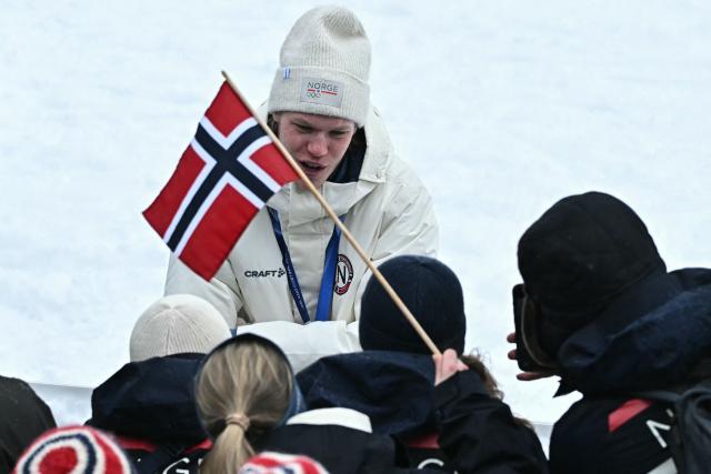 Gold medallist Norway's Andreas Skoglund celebrates with fans and a flag of Norway following the nordic combined team sprint large hill event at Tesero Cross Country Stadium at Lago di Tesero (Val di Fiemme) during the Milano Cortina 2026 Winter Olympic Games on February 19, 2026. (Photo by Javier SORIANO / AFP)