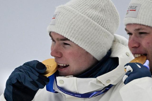 (From L) Gold medallist Norway's Jens Luraas Oftebro and Norway's Andreas Skoglund celebrate on the podium following the nordic combined team sprint large hill event at Tesero Cross Country Stadium at Lago di Tesero (Val di Fiemme) during the Milano Cortina 2026 Winter Olympic Games on February 19, 2026.  (Photo by Tobias SCHWARZ / AFP)