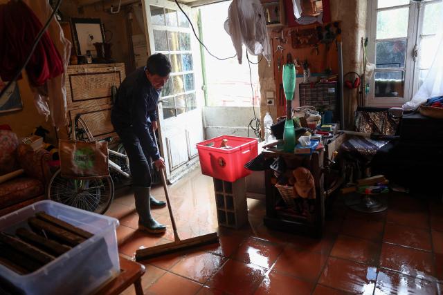 A man sweeps flood water out of a house following heavy rain and flooding of the Garonne river in Langoiran, western France, on February 19, 2026, as the region braces with the risk of further flooding as Storm Pedro approaches. Four departments in western France were placed under red alert over the risk of flooding, with officials expecting the situation to worsen with the arrival of Storm Pedro, which is poised to batter swathes of western Europe. (Photo by ROMAIN PERROCHEAU / AFP)