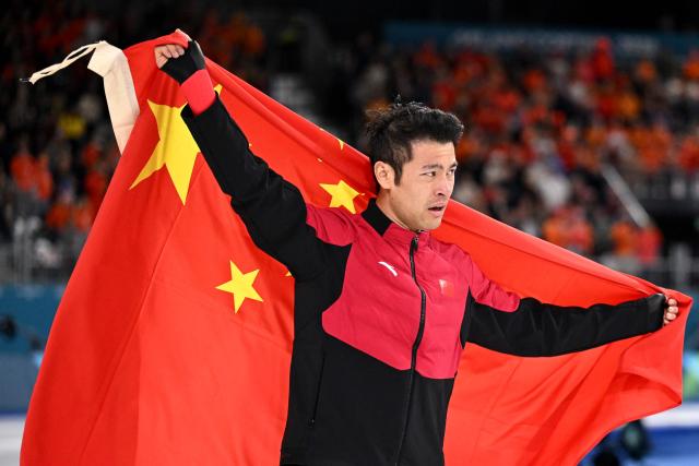 Gold medallist China's Ning Zhongyan celebrates with a flag of China after competing in the speed skating men's 1500m during the Milano Cortina 2026 Winter Olympic Games at Milano Speed Skating Stadium in Milan on February 19, 2026. (Photo by Daniel MUNOZ / AFP)