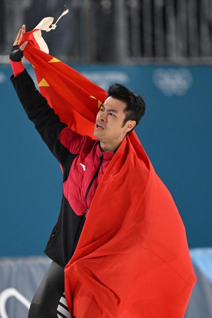 Gold medallist China's Ning Zhongyan celebrates with a flag of China after competing in the speed skating men's 1500m during the Milano Cortina 2026 Winter Olympic Games at Milano Speed Skating Stadium in Milan on February 19, 2026. (Photo by Daniel MUNOZ / AFP)