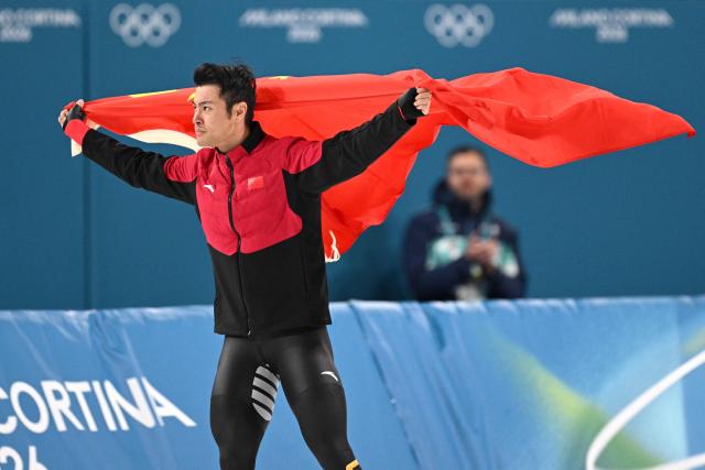 China's Ning Zhongyan waves his country's flag after winning gold in the speed skating men's 1500m during the Milano Cortina 2026 Winter Olympic Games at Milano Speed Skating Stadium in Milan on February 19, 2026. (Photo by Daniel MUNOZ / AFP)