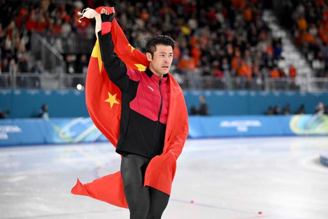 China's Ning Zhongyan holds his country's flag after winning gold in the speed skating men's 1500m during the Milano Cortina 2026 Winter Olympic Games at Milano Speed Skating Stadium in Milan on February 19, 2026. (Photo by Daniel MUNOZ / AFP)