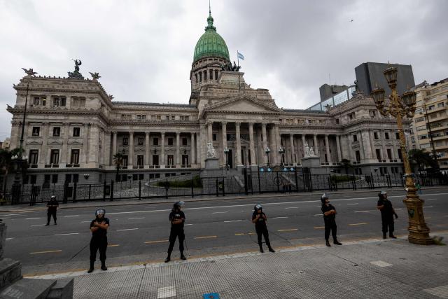 Police officers stand guard outside the Congress building, where Argentina's President Javier Milei's labour reform is to be treated, in Buenos Aires, on February 19, 2026. Shops and supermarkets closed, public transport was scarce and garbage went uncollected on February 19, 2026 as Argentine workers staged the fourth general strike of President Javier Milei's term, this time to protest labor reforms. (Photo by TOMAS CUESTA / AFP)