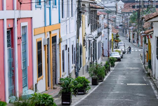 A man walks with a bicycle on a street in the San Antonio neighbourhood in Cali, Colombia on February 17, 2026. The San Antonio neighborhood, known as the heart of "Old Cali", is a historic and bohemian area of colonial architecture, famous for its colorful facades and its location on a hill with panoramic views of the city. (Photo by Joaquín SARMIENTO / AFP)